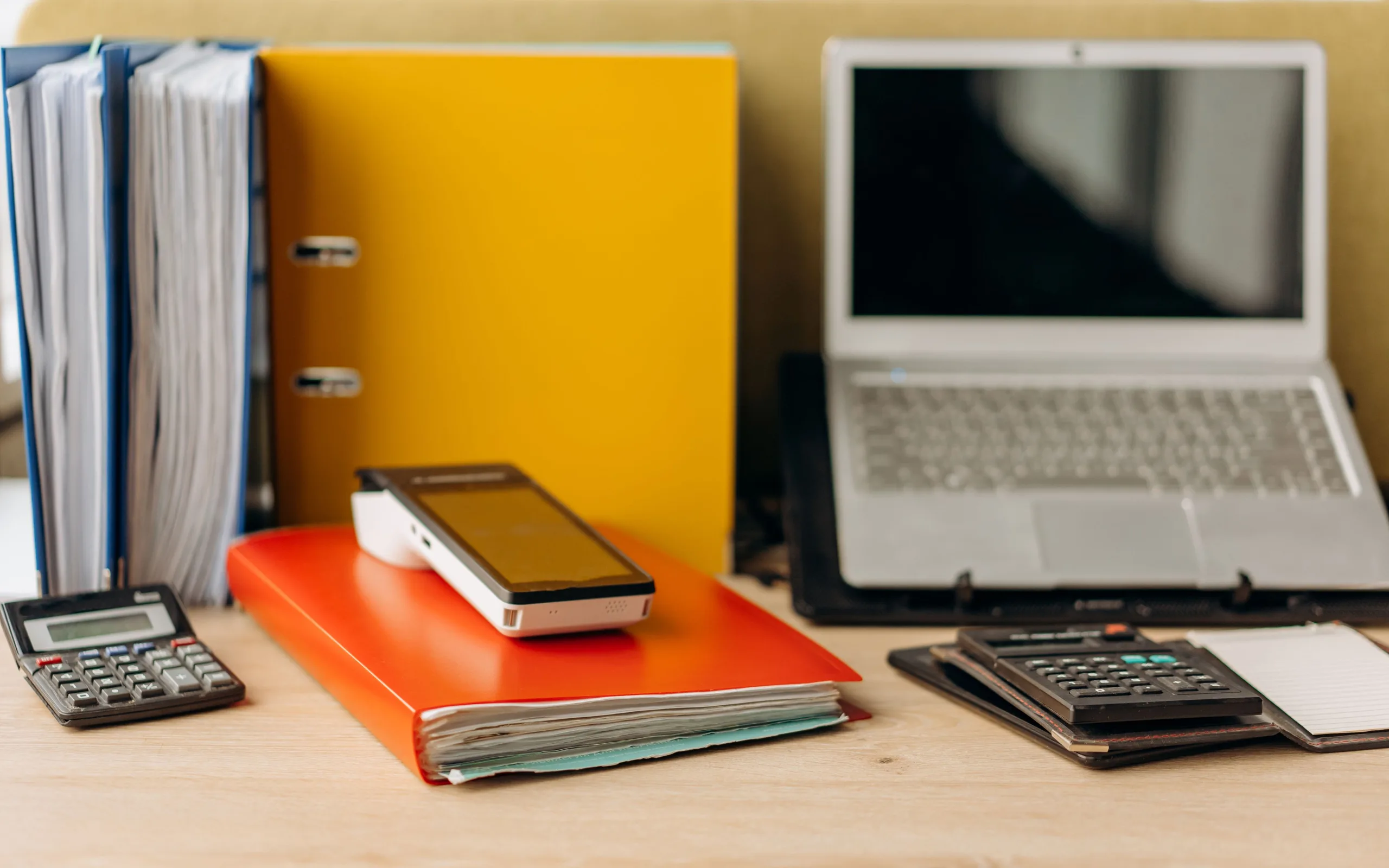 Poste de gestion avec ordinateur portable, factures et calculatrice dans un bureau de PME.